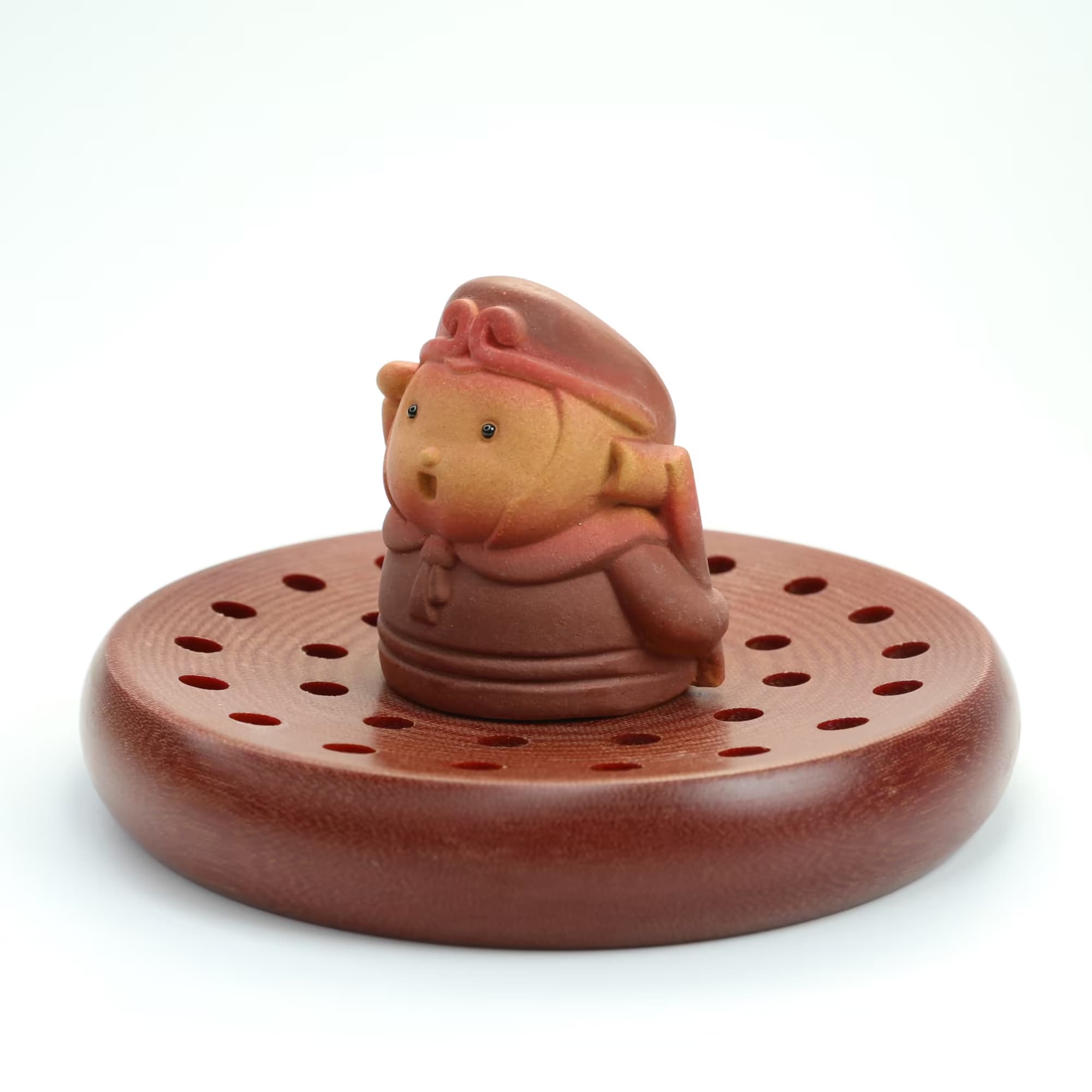 A Yixing zisha tea pet resting on a wooden gongfu tea tray